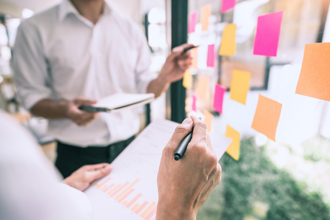 Business people meeting at office and use sticky notes on glass wall in office, diverse employees people group planning work together brainstorm strategy