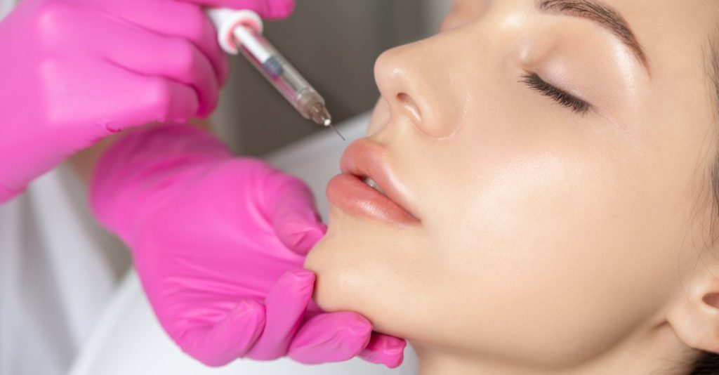 Person with big lips receiving lip fillers in med spa office