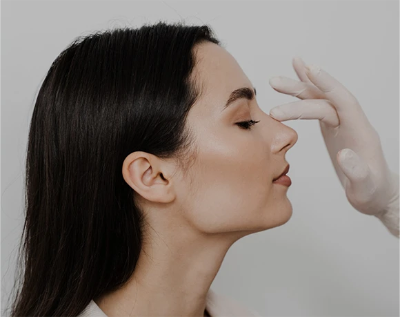 Profile view of a woman with eyes closed as a hand demonstrates a facial aesthetic treatment near her forehead